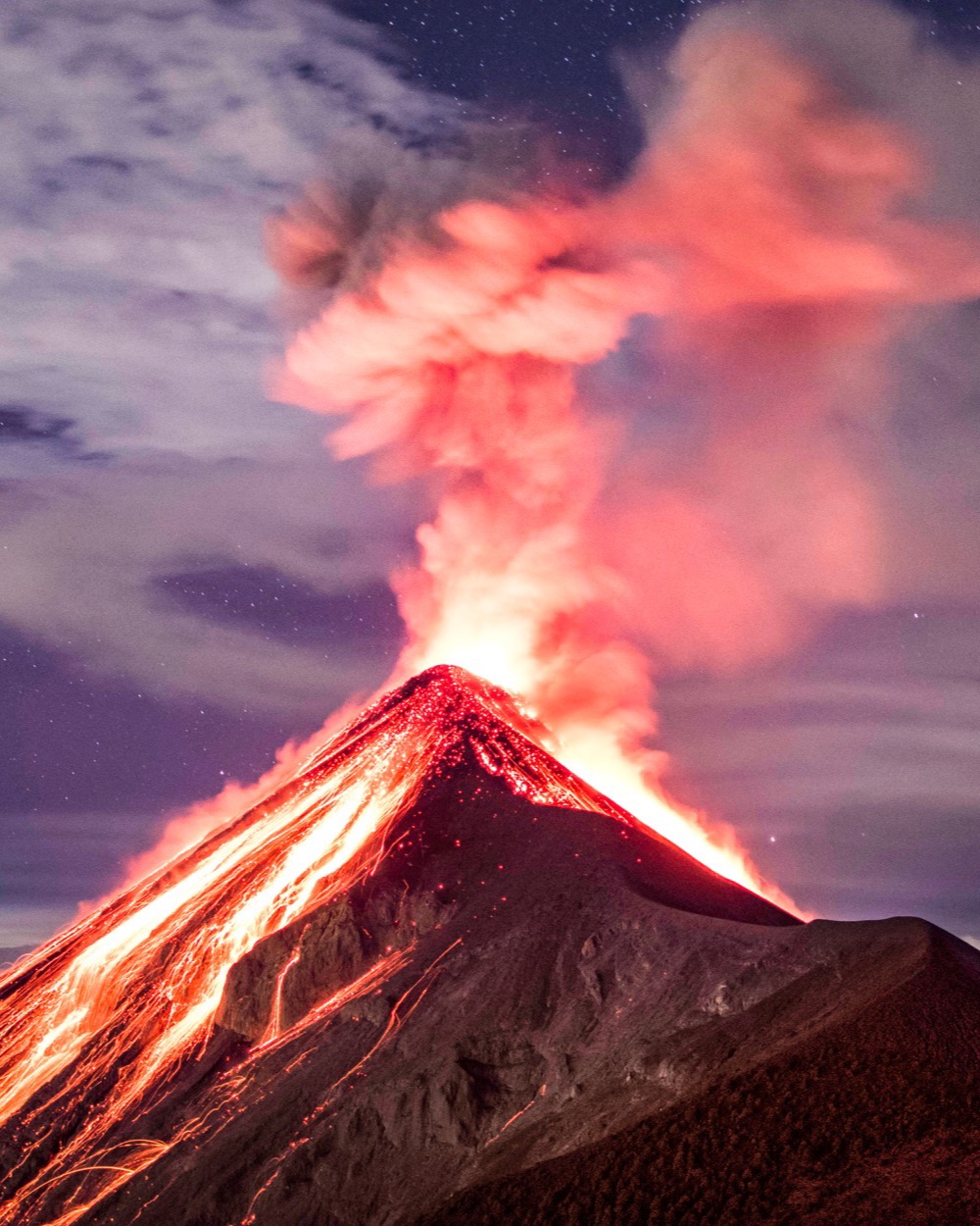 Volcán de Fuego erupting at night with glowing lava flows